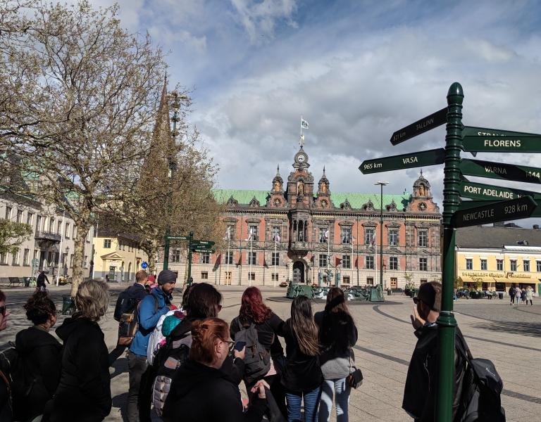 students standing in foreign city near sign post