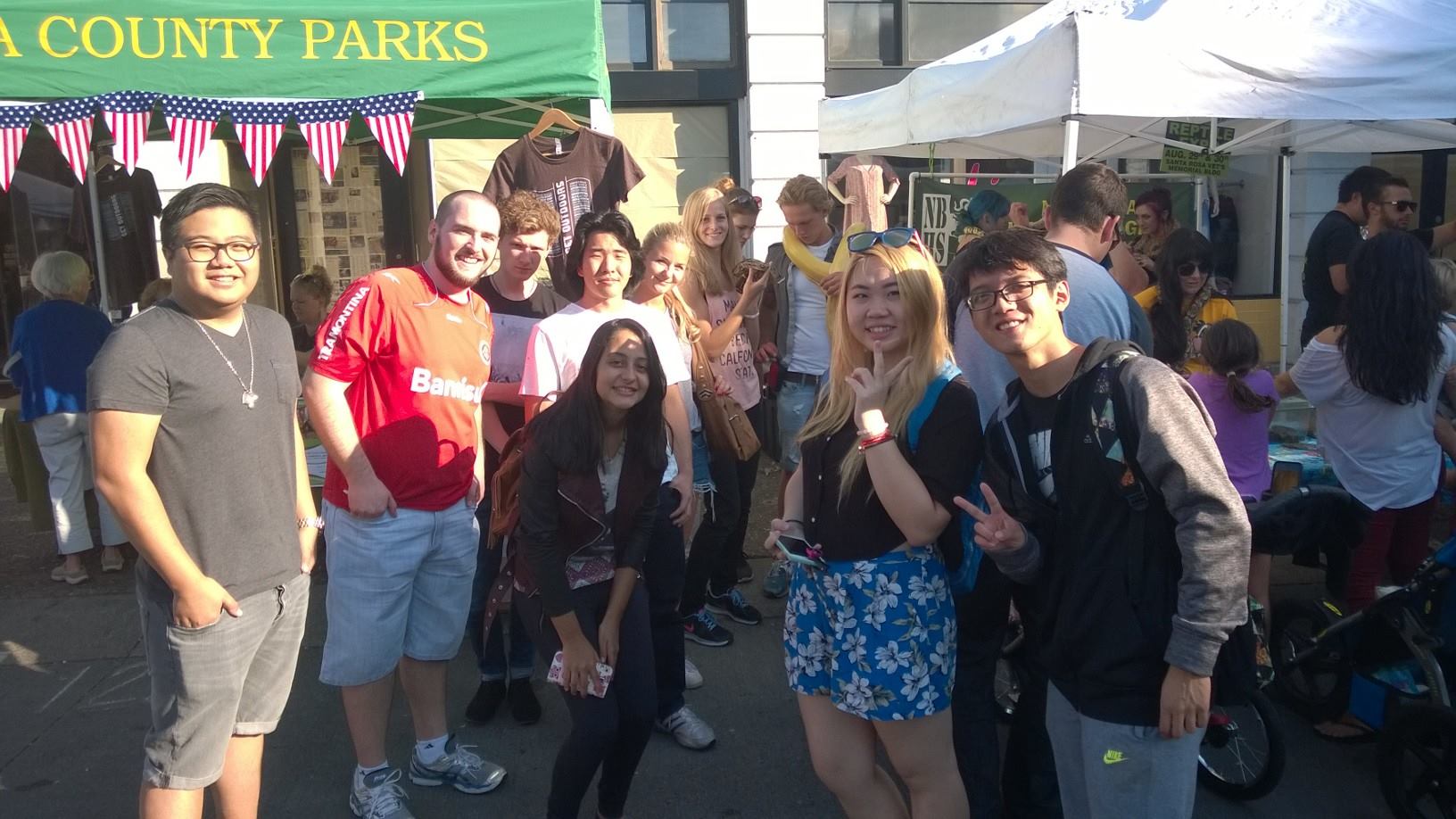 International Students visiting animal booth at Santa Rosa Wednesday Night Market. One student in the back is holding a large, yellow python