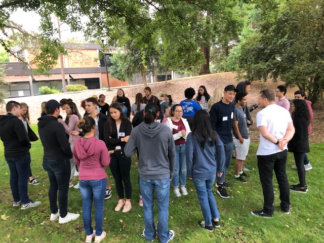 International students stand in a circle talking happily to each other.