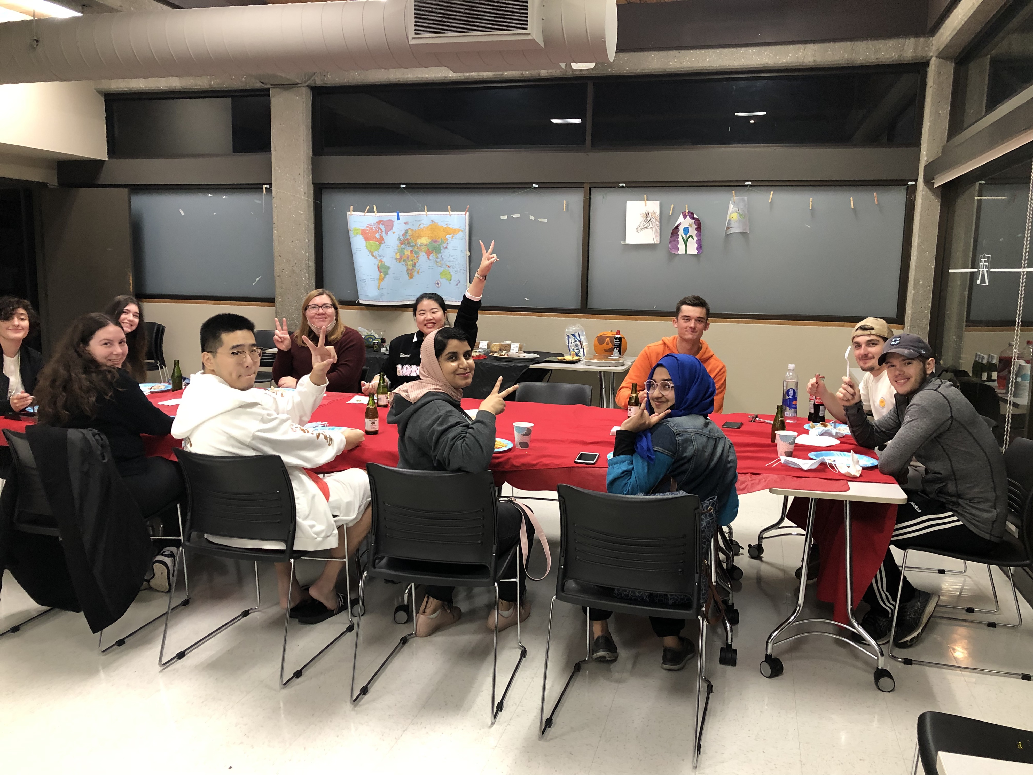 Students gather around table smiling for Friendsgiving.