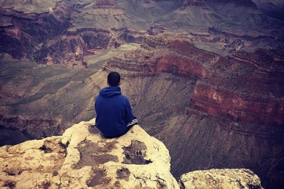 Evan sitting at the edge of a canyon looking out to the scenery