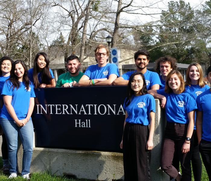Group of student ambassador stand around International Hall sign.