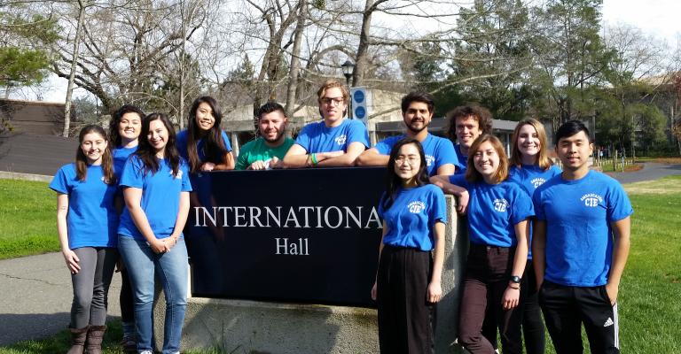 Group of student ambassador stand around International Hall sign.