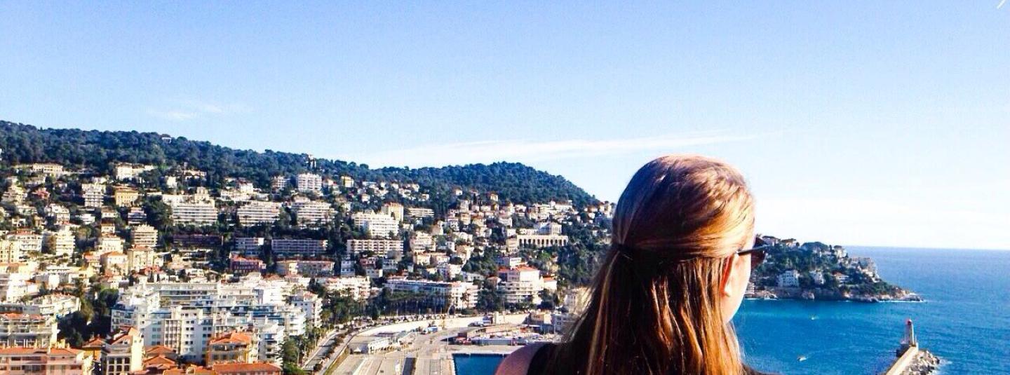Study abroad student looks out over city and coast in Nice, France.