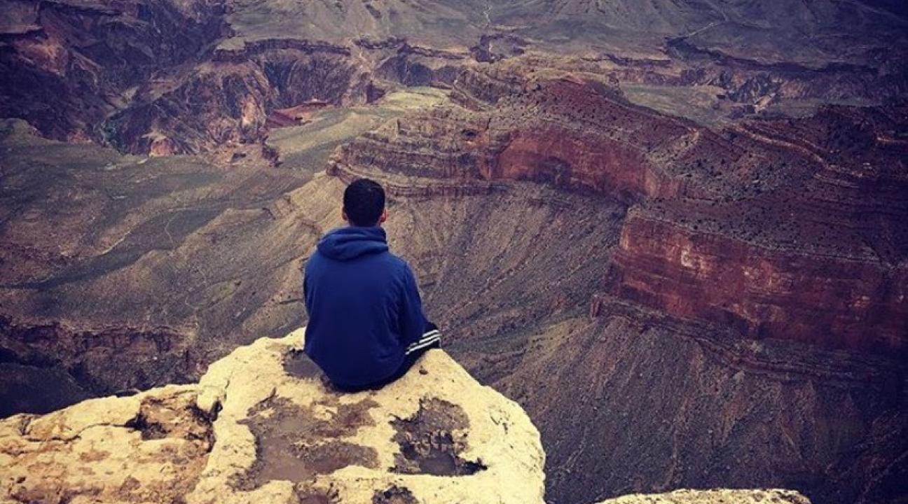 Evan sitting at the edge of a canyon looking out to the scenery