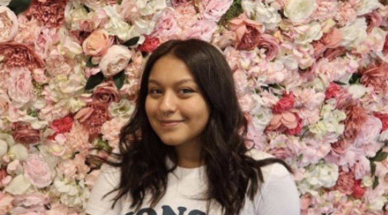 Gloria stands in front of a wall of roses with Yonsei University t-shirt on