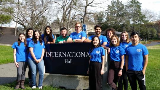 Group of student ambassador stand around International Hall sign.