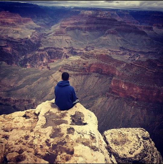 Evan sitting at the edge of a canyon looking out to the scenery